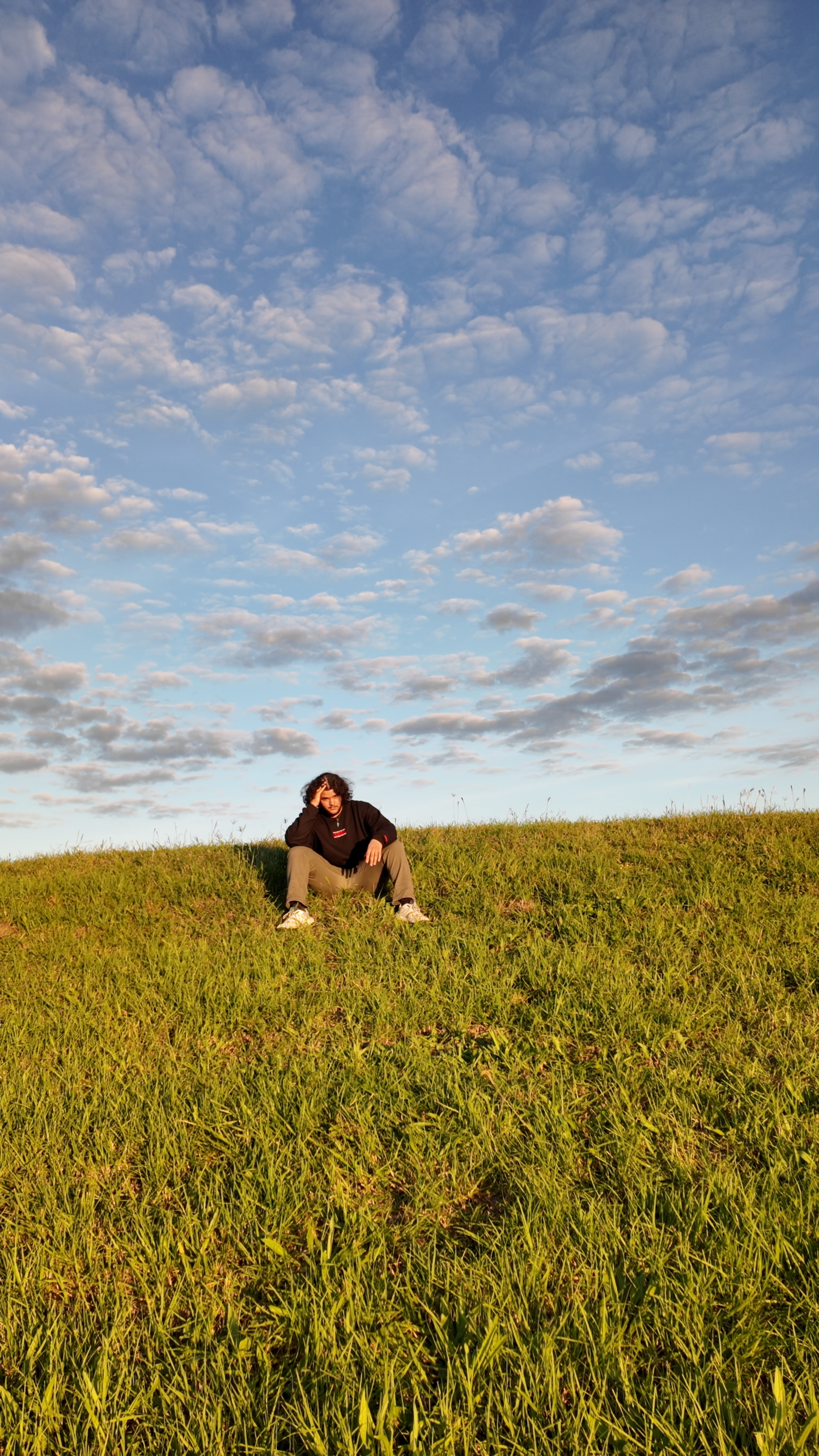 Model wearing Christian apparel sitting on a Hill – "Nothing Without Jesus Christ" Embroidered on a cozy sweatshirt